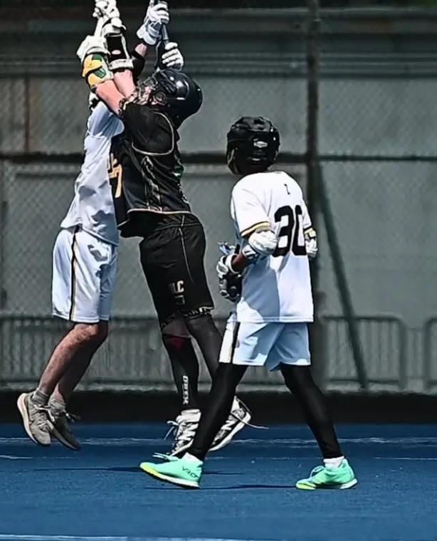 Two players leap for a high ball on a blue pitch